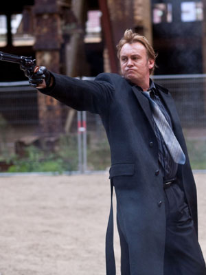 Philip Glenister as Gene Hunt aims a gun