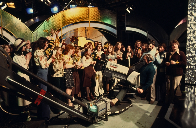 A camera films audience members in the Top of the Pops studio. 