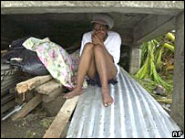 A Grenadian girl sits below her home after the roof was blown off by Hurricane Ivan