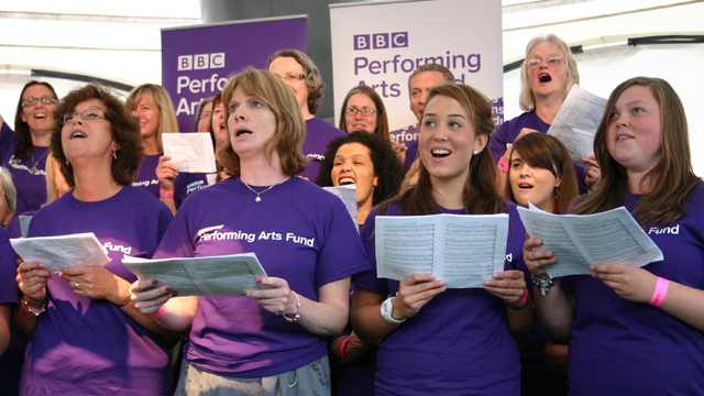 BBC Performing Arts Fund choir performing in purple t-shirts at Potterrow site.