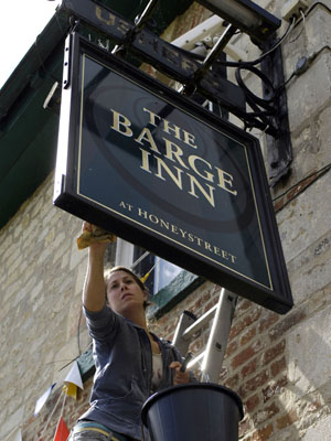 A volunteer polishes the Barge Inn sign