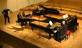 Photo of Urmas Sisask in mid-air with the Estonian Piano Orchestra