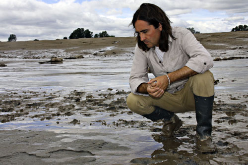 Neil Oliver looking at footprints in the mud in Newport