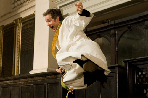 Rev. Adam Smallbone (Tom Hollander) jumps over a pew