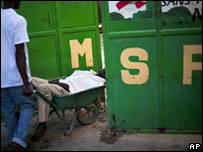 Ill Haitian in wheelbarrow being taken into Medecins Sans Frontiers treatment centre