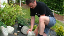 man putting rocks in a garden