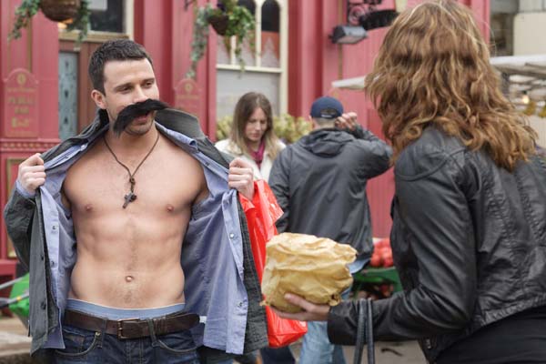 EastEnders' Ryan Malloy, played by Neil McDermott, unbuttons his shirt to reveal his torso to Janine Butcher, played by Charlie Brooks, in the middle of Albert Square. EastEnders will be broadcast in HD by the end of the year
