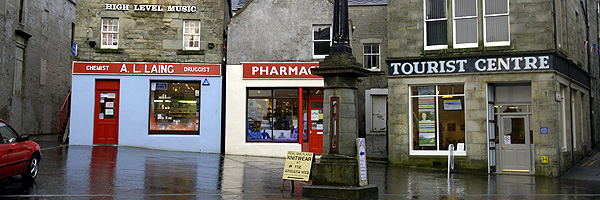 A deserted square in Lerwick. A single lamp-post in the centre with a small bank of shops around the perimetre